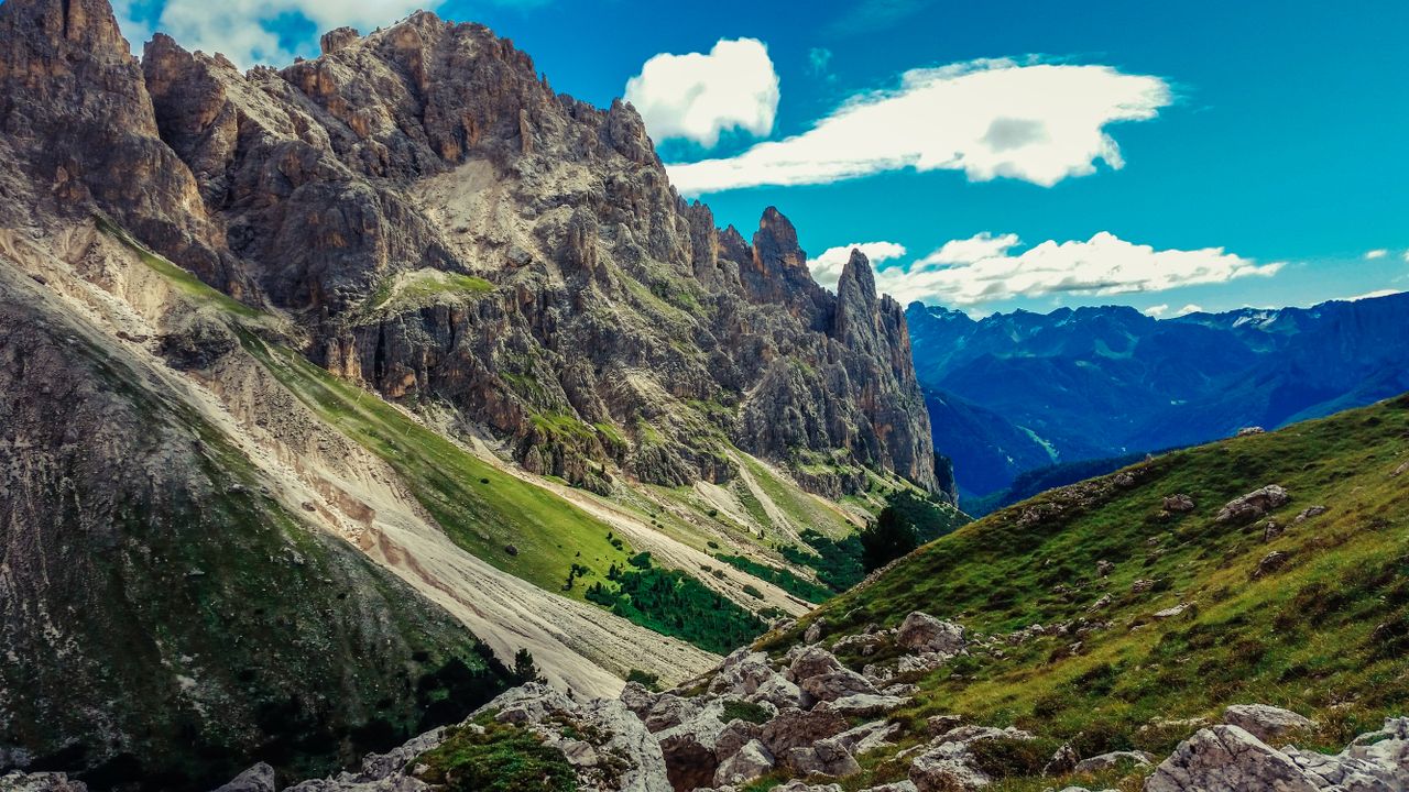 Breathtaking view of the Dolomite mountains with vibrant blue sky and lush greenery.