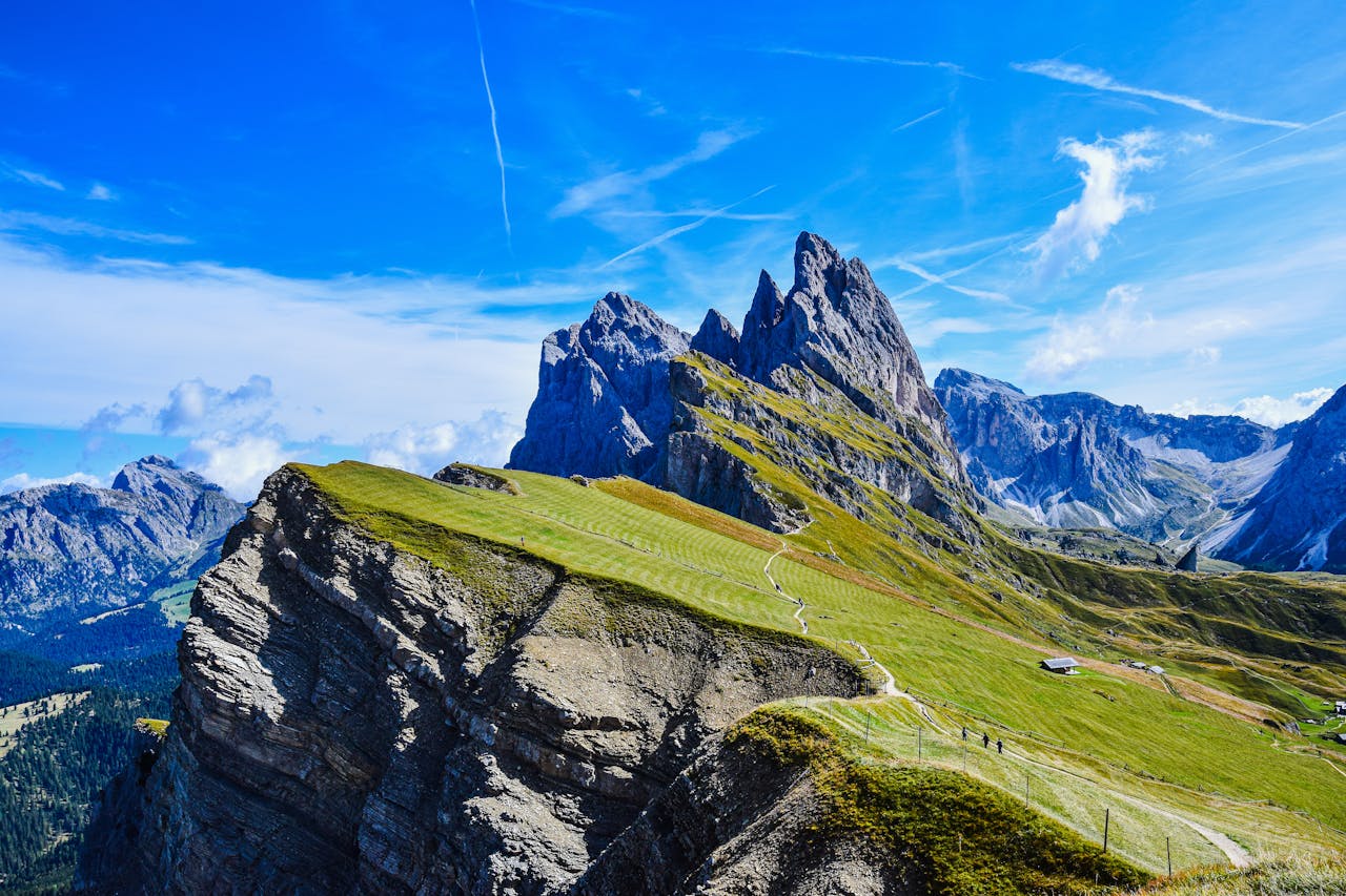 Stunning aerial view of the Dolomite peaks and lush meadows under a clear blue sky.
